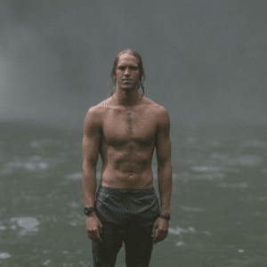 Young man standing in the waterfall